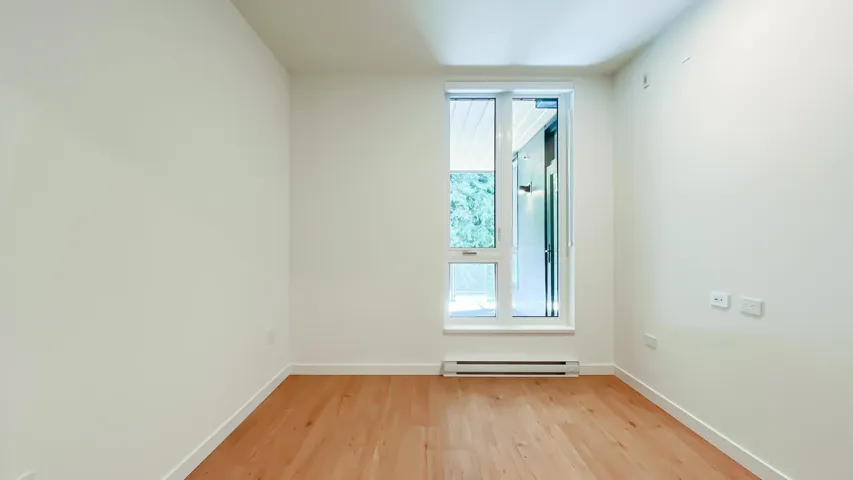 Empty room with light wood finished floors and a baseboard heating unit