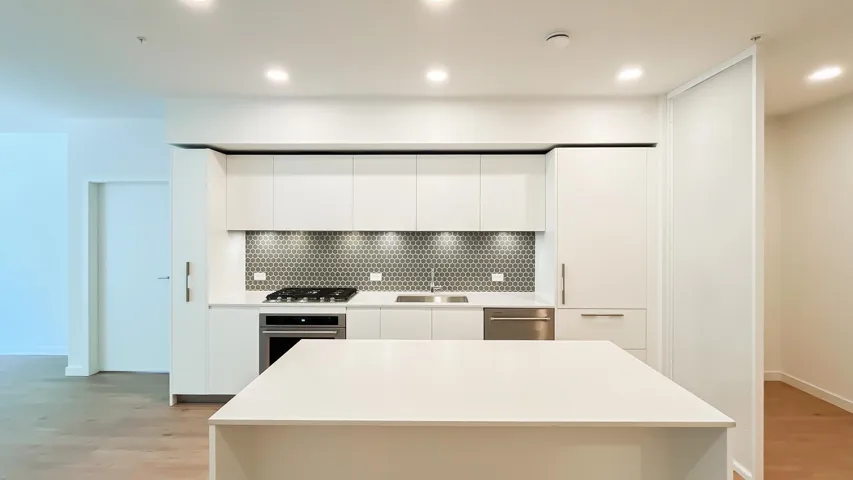 Kitchen featuring modern cabinets, light wood finished floors, backsplash, appliances with stainless steel finishes, and white cabinetry
