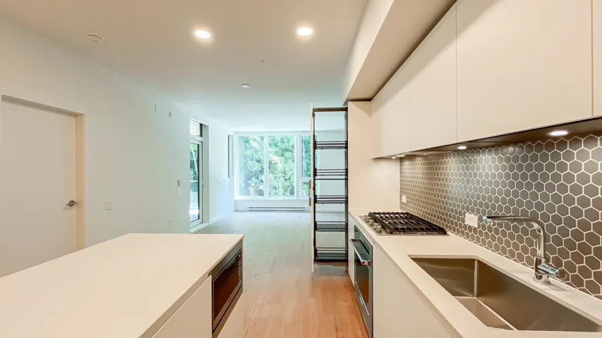 Kitchen with white cabinetry, light wood-style flooring, tasteful backsplash, light countertops, and stainless steel appliances