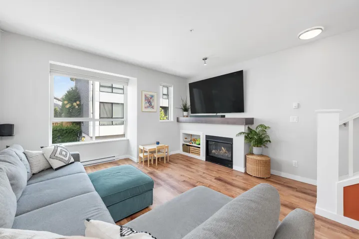 Living area featuring light wood-style floors, a glass covered fireplace, and a baseboard radiator