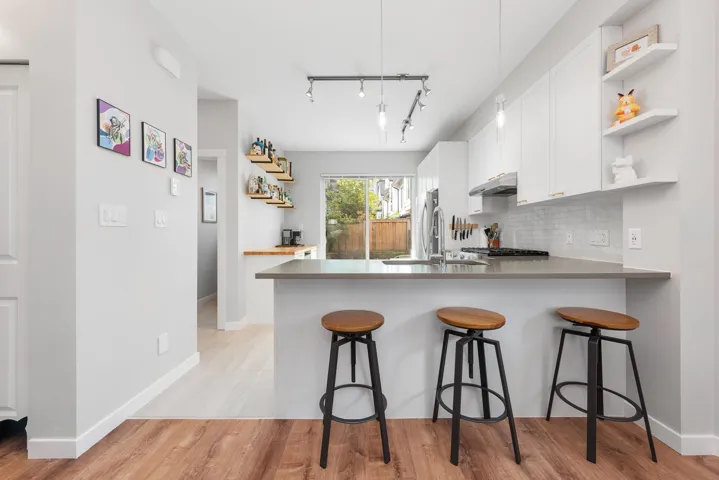 Kitchen featuring open shelves, a peninsula, tasteful backsplash, and a breakfast bar area