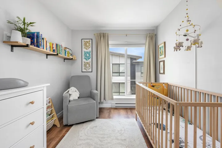 Bedroom with dark wood-type flooring, a nursery area, and baseboard heating