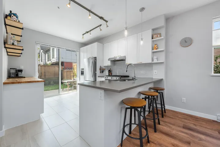 Kitchen featuring healthy amount of natural light, open shelves, a peninsula, and decorative light fixtures
