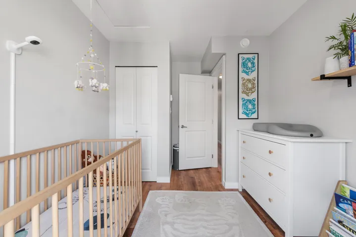 Bedroom featuring dark wood finished floors, a closet, and a nursery area