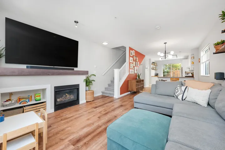 Living room with a glass covered fireplace, wood finished floors, stairway, a chandelier, and recessed lighting