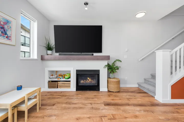 Living room with stairs, wood finished floors, and a glass covered fireplace