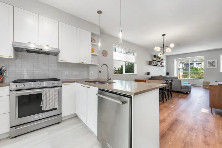 Kitchen with appliances with stainless steel finishes, open shelves, tasteful backsplash, pendant lighting, and under cabinet range hood