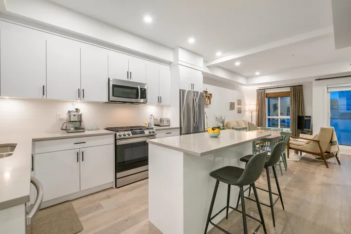 Kitchen with stainless steel appliances, a breakfast bar, light wood-type flooring, backsplash, and a kitchen island