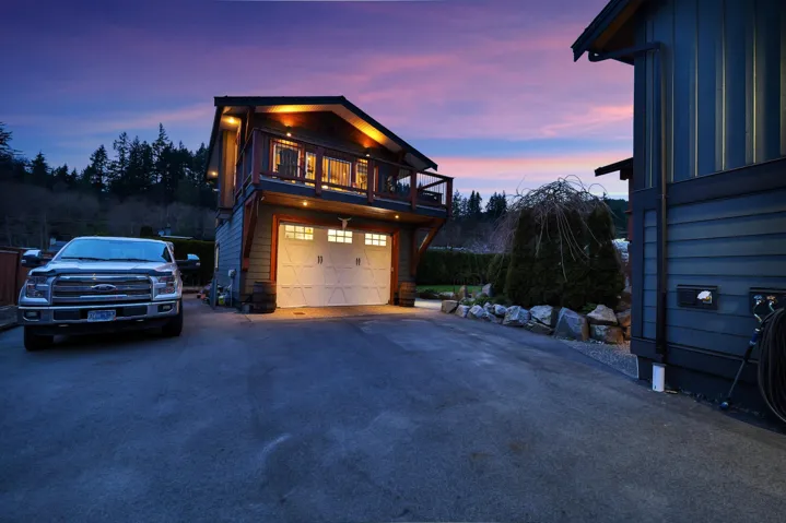 Property exterior at dusk featuring board and batten siding, asphalt driveway, a wooden deck, and a garage
