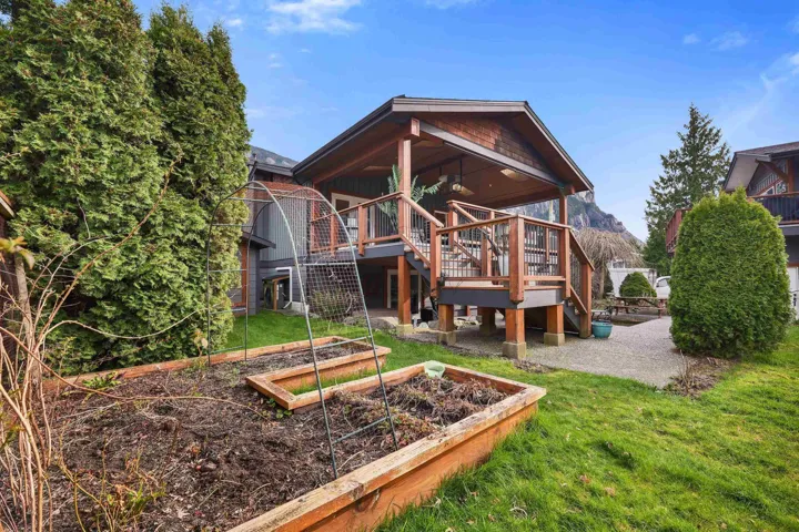 Back of house featuring a yard, a vegetable garden, a wooden deck, board and batten siding, and a patio area