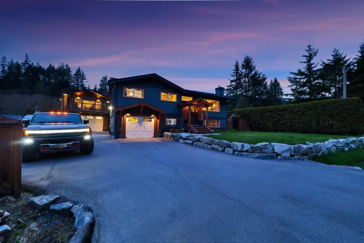 View of front of property featuring a chimney, asphalt driveway, a front lawn, and a garage