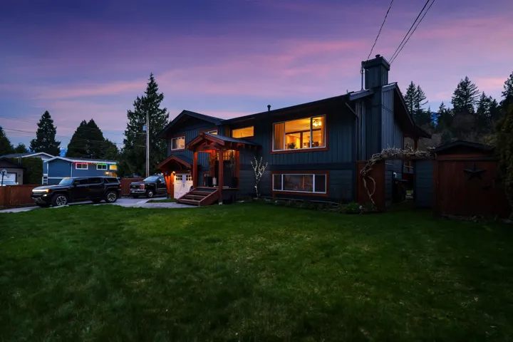 Back of property at dusk with a chimney, a lawn, and a shed