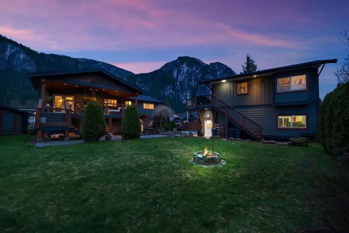 Back of property with a deck with mountain view, a lawn, and board and batten siding