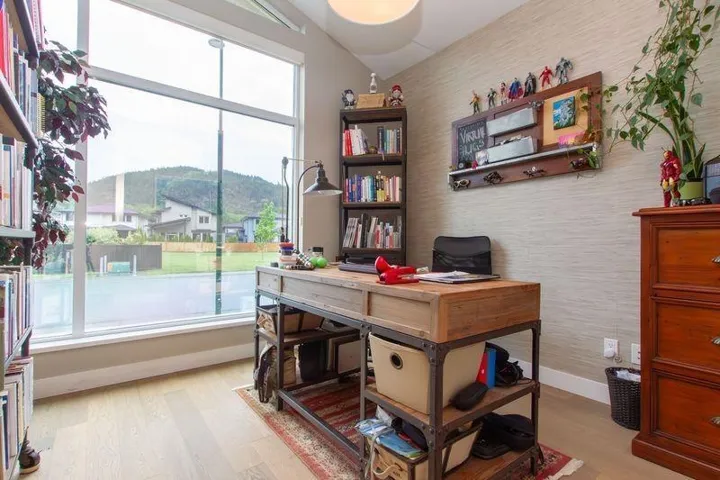 Home office with lofted ceiling, baseboards, wood finished floors, and wallpapered walls