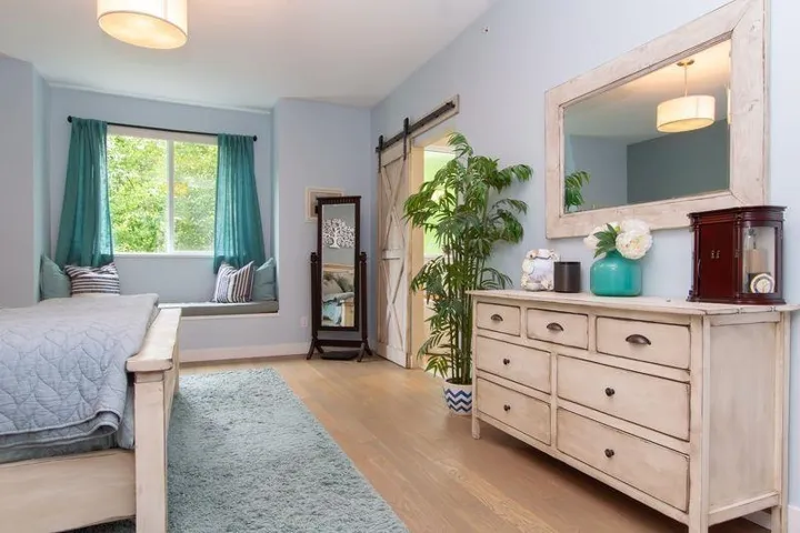 Bedroom with light wood-type flooring, baseboards, and a barn door
