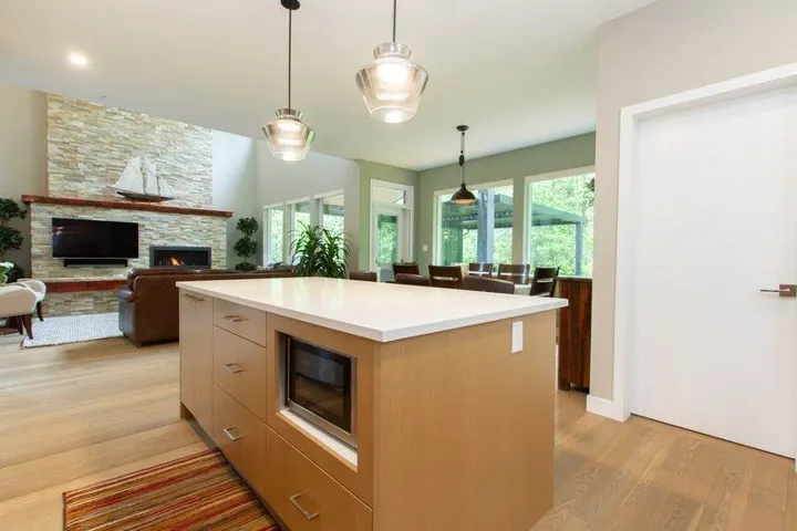 Kitchen with light wood-style flooring, decorative light fixtures, a center island, light countertops, and a fireplace