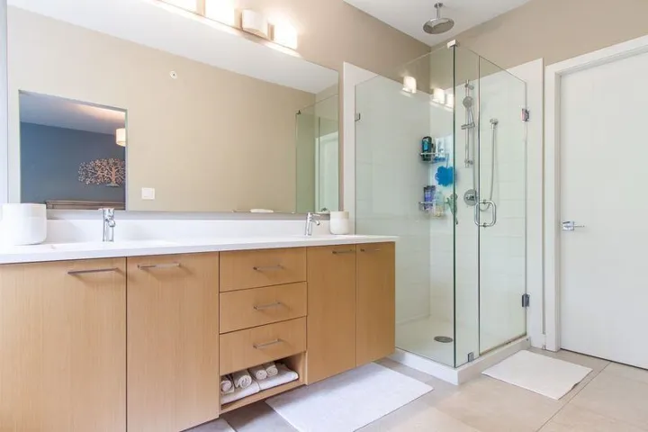 Bathroom with tile patterned flooring, a sink, a shower stall, and double vanity