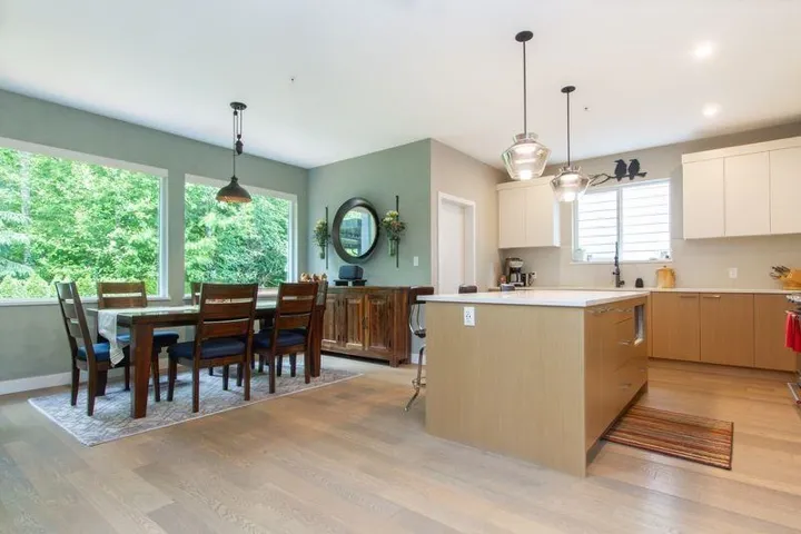 Kitchen with light wood-style flooring, a kitchen island, modern cabinets, light countertops, and white cabinetry