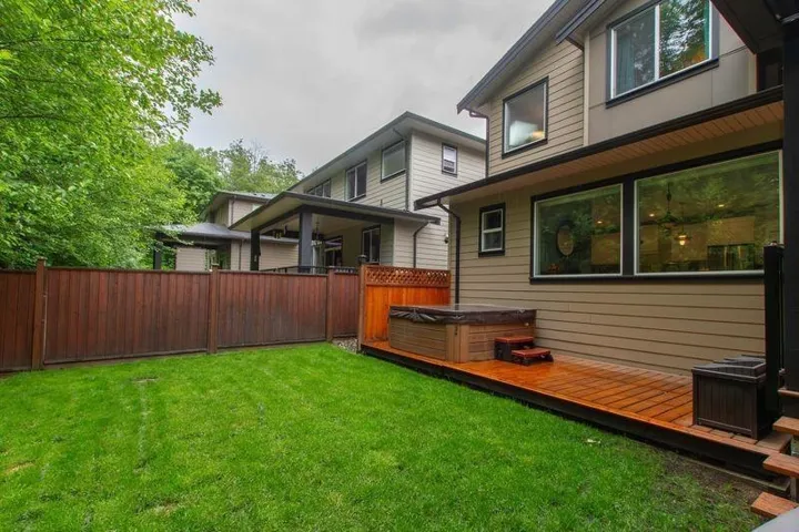 View of yard with fence, a wooden deck, and a hot tub