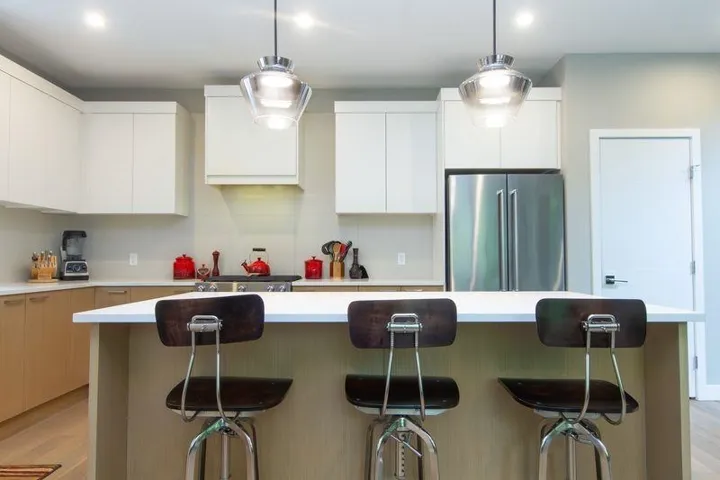 Kitchen with freestanding refrigerator, light countertops, and modern cabinets