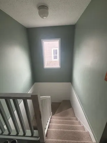 Staircase with a textured ceiling and carpet floors