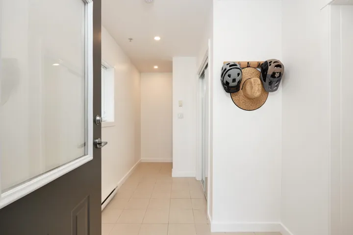 Corridor with recessed lighting, light tile patterned floors, a baseboard heating unit, and baseboards