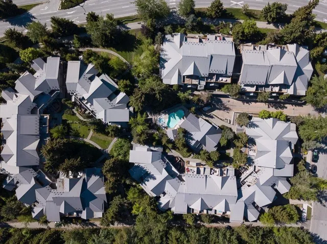 Community featuring multi-level rooflines, mature landscaping, paved pathways, and a central swimming pool
