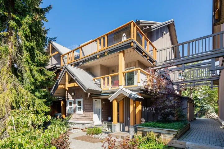 Multi-level exterior featuring wood siding, a metal roof, and a second-story balcony with glass railings
