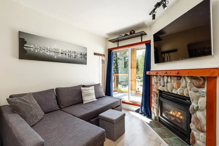 Stone-clad fireplace with wood surround and hearth, track lighting, and a sliding glass door