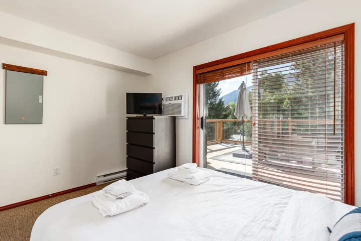 Glass sliding door with wood-finish trim, wood-finish blinds, and outdoor deck access