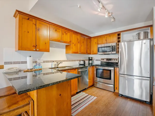 Kitchen featuring a peninsula, brown cabinetry, stainless steel appliances, and a sink