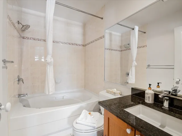 Bathroom featuring toilet, shower / tub combo with curtain, and vanity