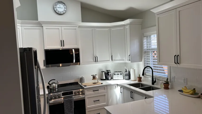 Kitchen featuring shaker-style white cabinetry, stone-finish countertops, stainless steel appliances, a white tile backsplash, and a matte black gooseneck faucet