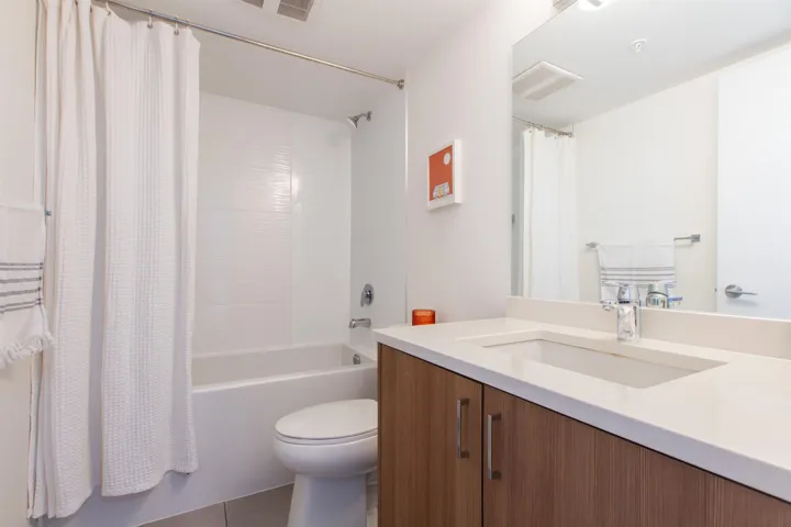 Bathroom featuring vanity, visible vents, shower / tub combo, tile patterned floors, and toilet