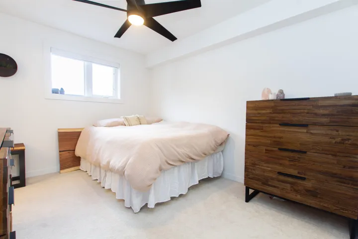 Bedroom featuring baseboards, light colored carpet, and a ceiling fan