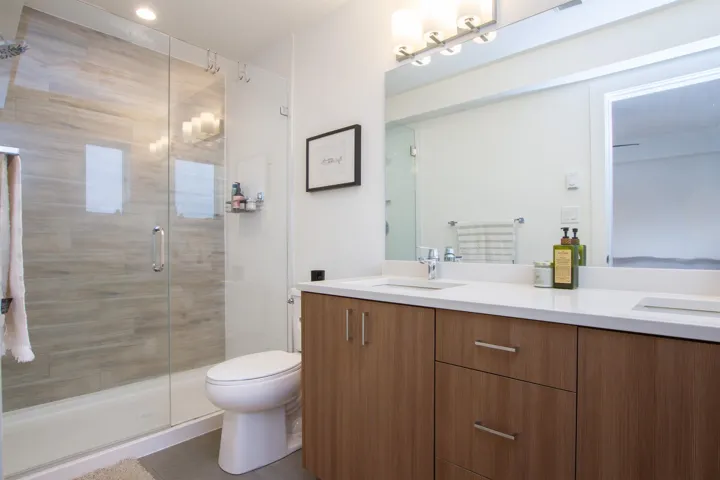 Full bathroom with double vanity, a shower stall, and a sink