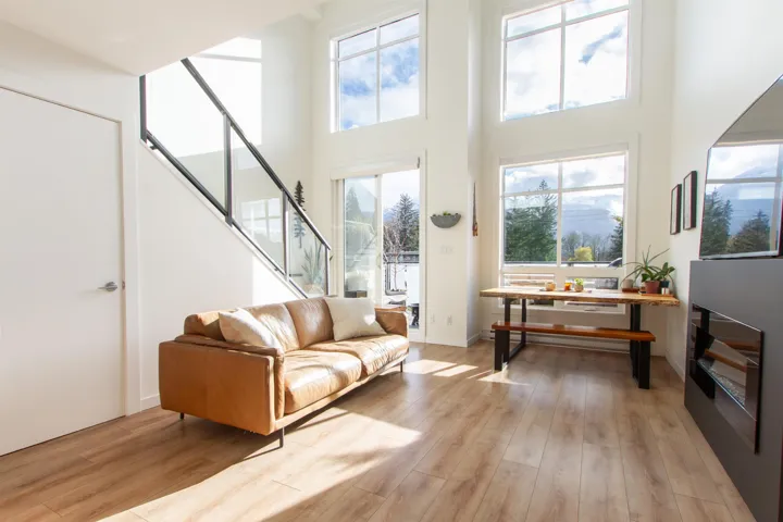 Living area with stairs, a high ceiling, light wood-style floors, and baseboards
