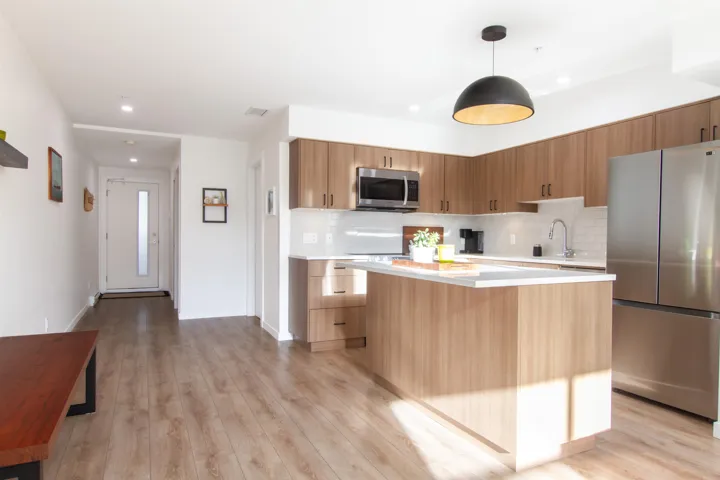 Kitchen with light wood-type flooring, modern cabinets, stainless steel appliances, light countertops, and decorative backsplash