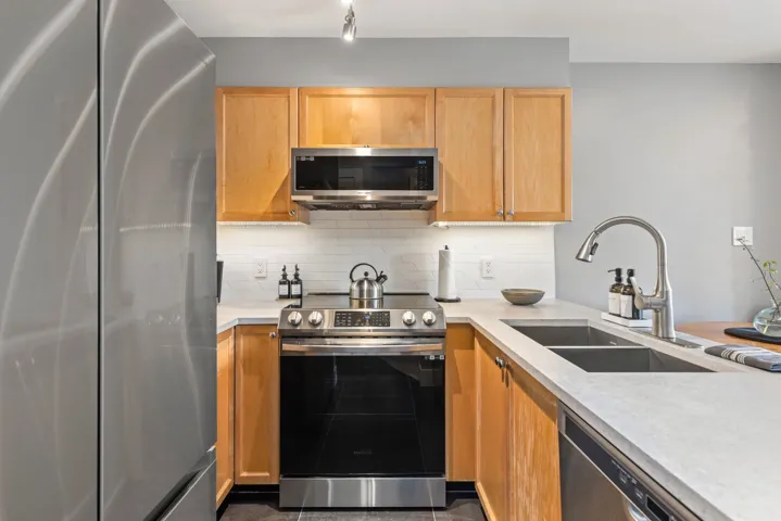 Kitchen featuring light brown cabinets, light countertops, tasteful backsplash, a sink, and stainless steel appliances