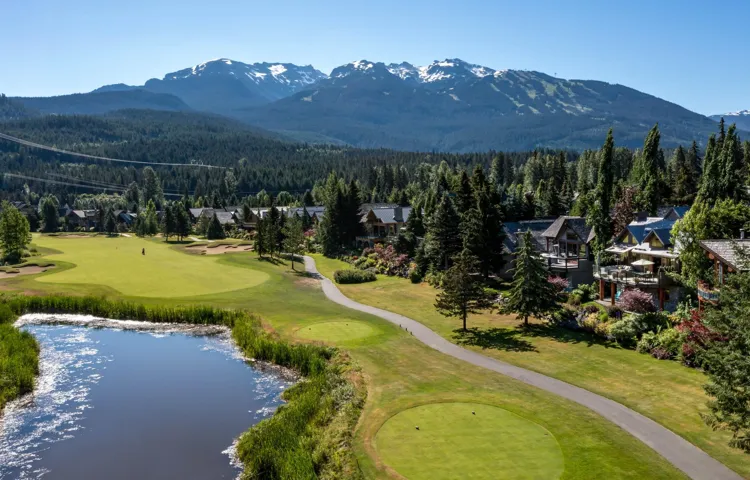 Aerial view with a view of trees, a water and mountain view, and golf course view