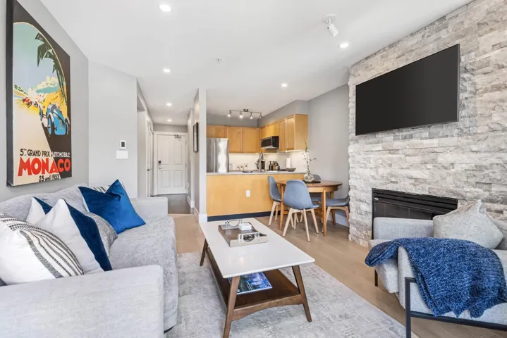 Living area with light wood-type flooring, recessed lighting, and a stone fireplace