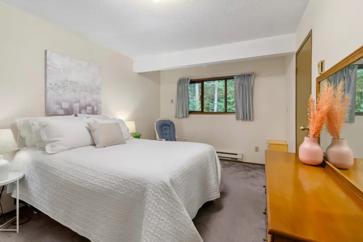 Carpeted bedroom with a textured ceiling and baseboard heating
