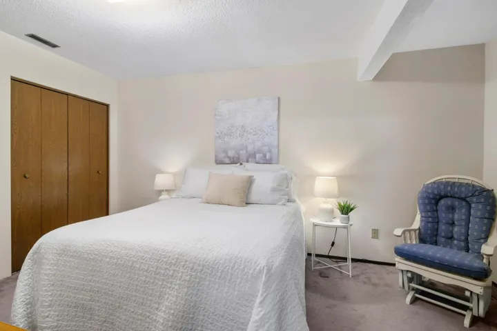 Bedroom with visible vents, beamed ceiling, a textured ceiling, carpet floors, and a closet