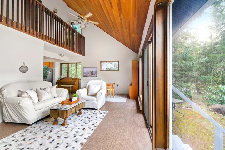 Living area featuring high vaulted ceiling, wooden ceiling, and a ceiling fan