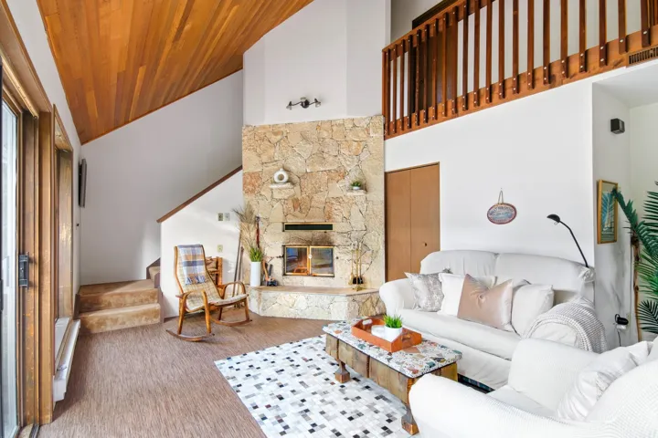 Living area with wooden ceiling, stairs, a fireplace, and high vaulted ceiling