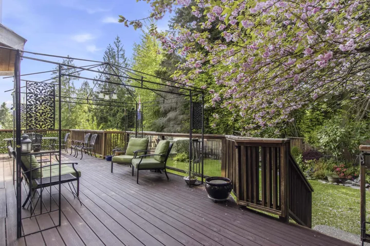 Expansive outdoor deck featuring wood-finish flooring, a decorative metal gazebo frame, and a surrounding wood railing
