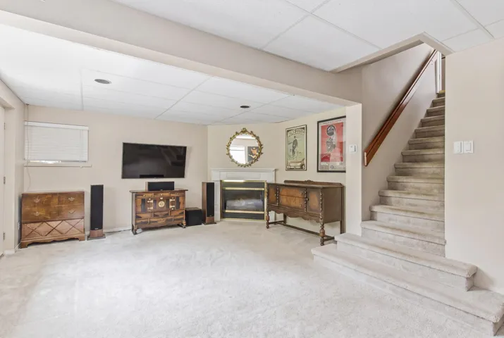 Spacious carpeted room featuring a white drop ceiling with recessed lighting