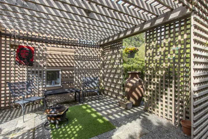 Outdoor patio featuring a slatted pergola, latticework privacy screens, and a concrete paver surface