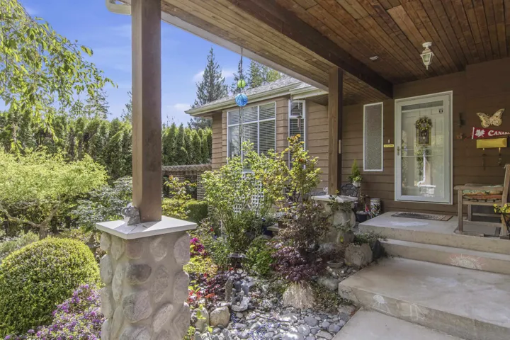 Covered porch entrance with concrete steps and a rock-clad column base