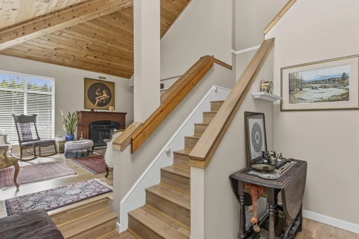Split-level interior featuring wood-finish flooring, a vaulted wood-plank ceiling, and a fireplace with a detailed wood mantel